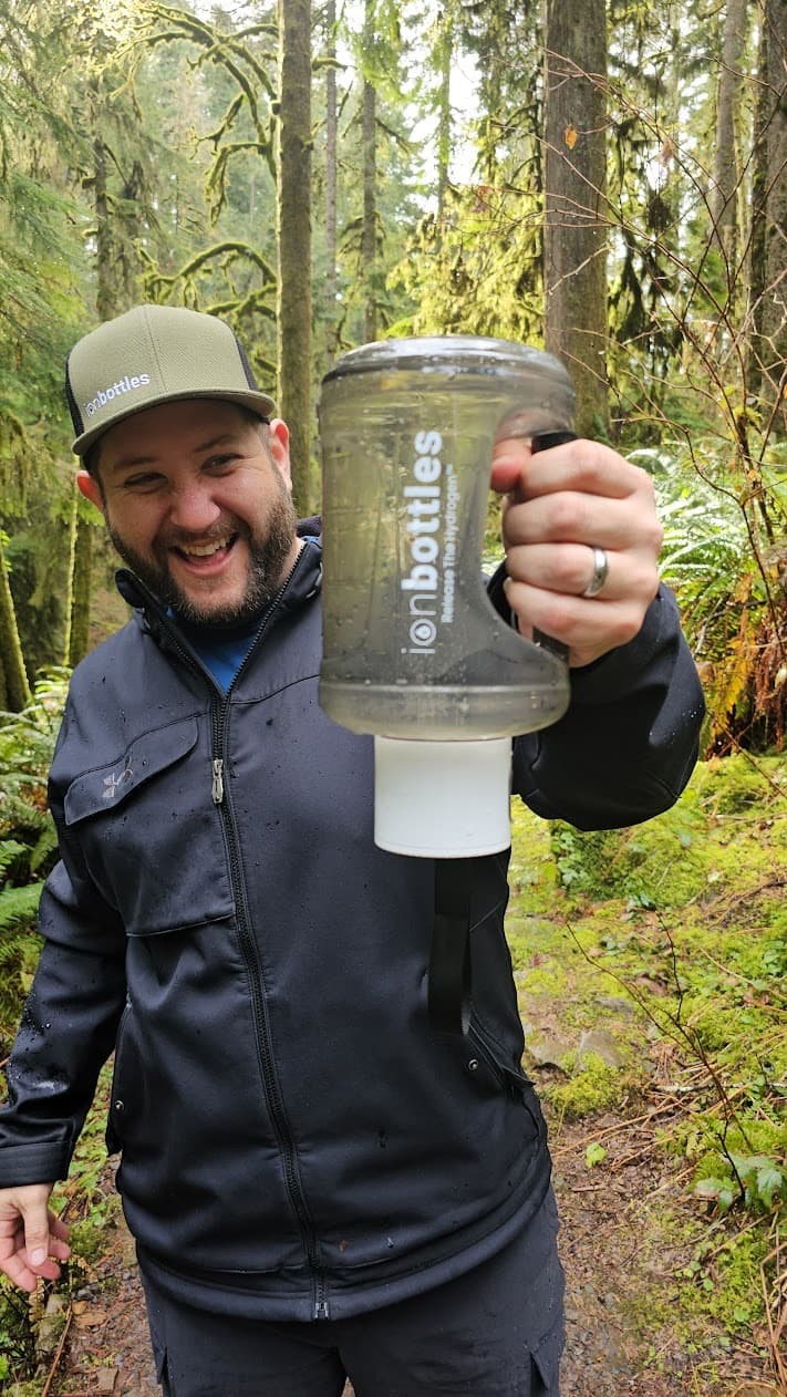 Bobby Samai holding an ionbottles jug in the woods